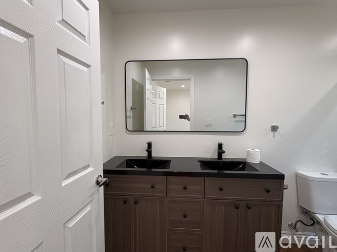 A bathroom with a white door, a brown vanity, and a round mirror.