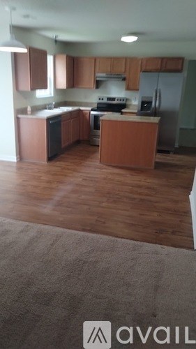 A kitchen with wooden floors and a rug in the foreground.