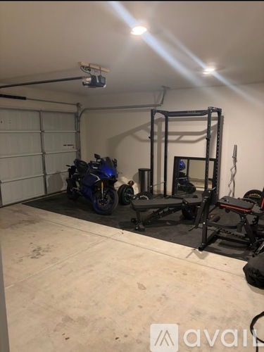 A garage with a motorcycle and a gym setup.