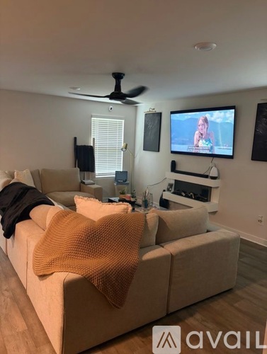 A living room with a beige couch and a television mounted on the wall.