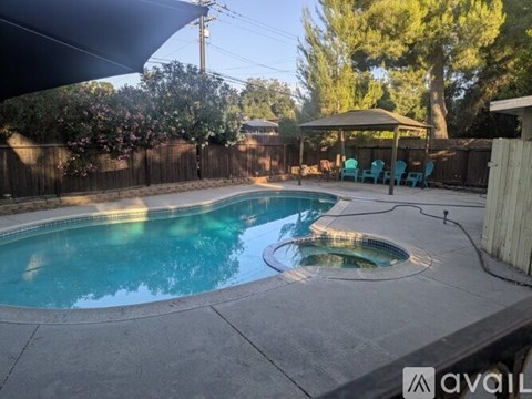A pool with a hot tub and a gazebo in the backyard.