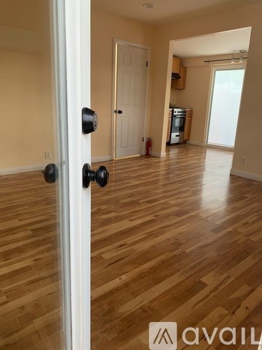 A room with wooden flooring and a door with a black handle.