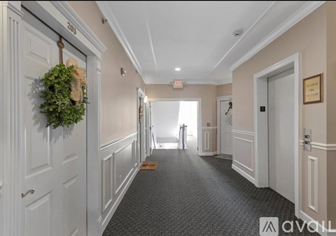 A hallway with a green plant hanging on the door and a sign that says "EXIT" on the wall.