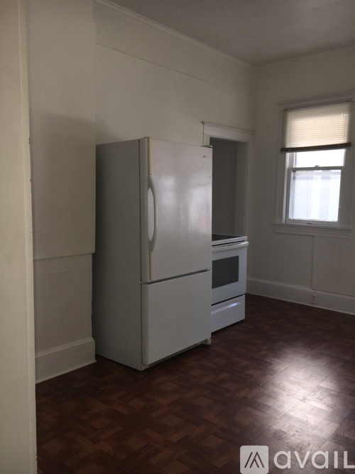 A white refrigerator in a room with a wooden floor.
