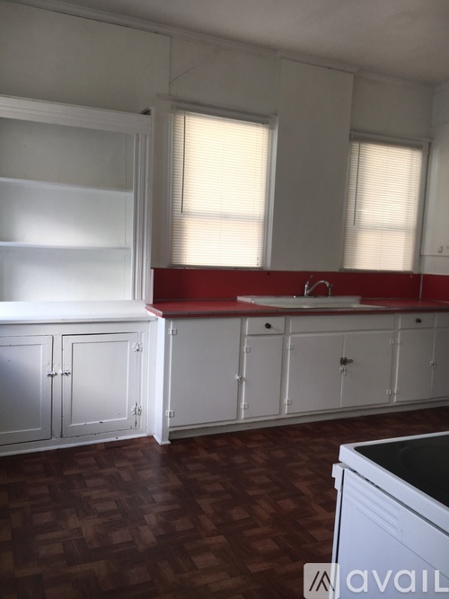 A kitchen with white cabinets and a red backsplash.