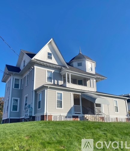 A large, two-story house with a grey and white exterior and a black roof.