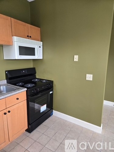 A kitchen with a black stove and a white microwave.