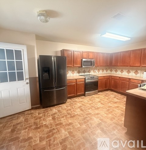 A kitchen with wooden cabinets and a black fridge.