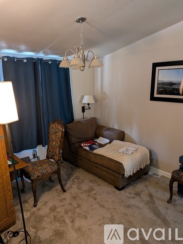 A living room with a brown couch, a chair, a lamp, and a picture on the wall.
