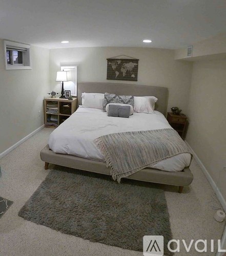 A bedroom with a large bed and a nightstand with a lamp.