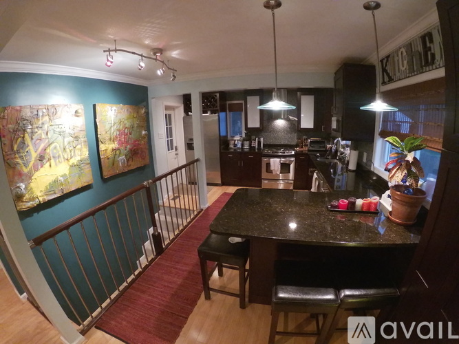 A kitchen with a table and chairs in the foreground and a painting on the wall.