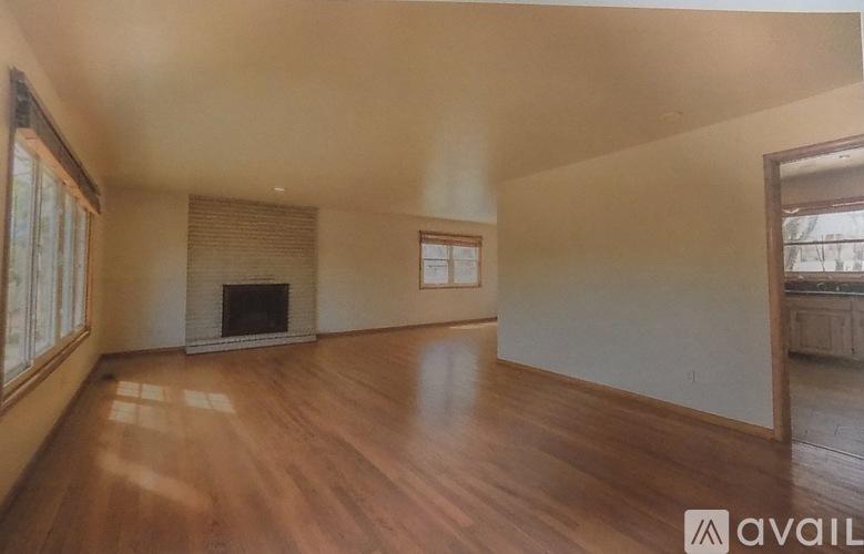 A spacious room with wooden floors and a fireplace.