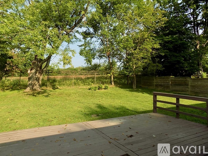 A wooden deck overlooks a grassy area with trees.