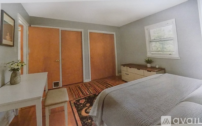 A bedroom with a bed, a desk, and a chair.