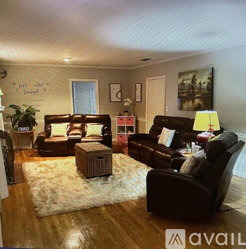 A living room with brown leather furniture and a rug.