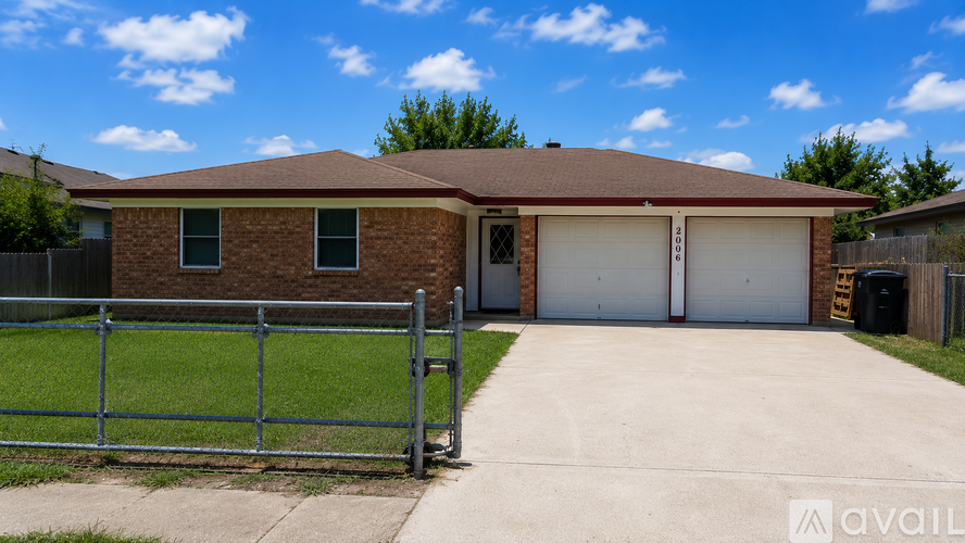 A house with a brown roof and a grey fence in front of it.
