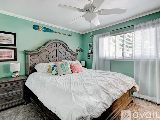 A bedroom with a white bed and a ceiling fan.