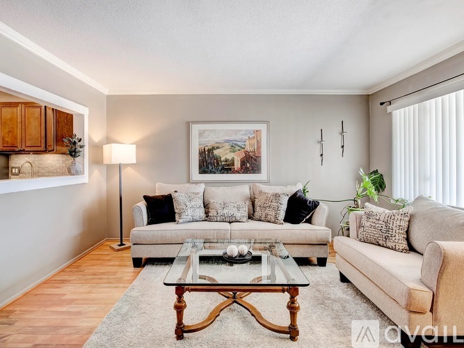 A living room with a white couch, a coffee table, and a painting on the wall.