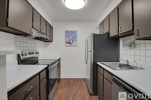 A kitchen with brown cabinets and a black refrigerator.