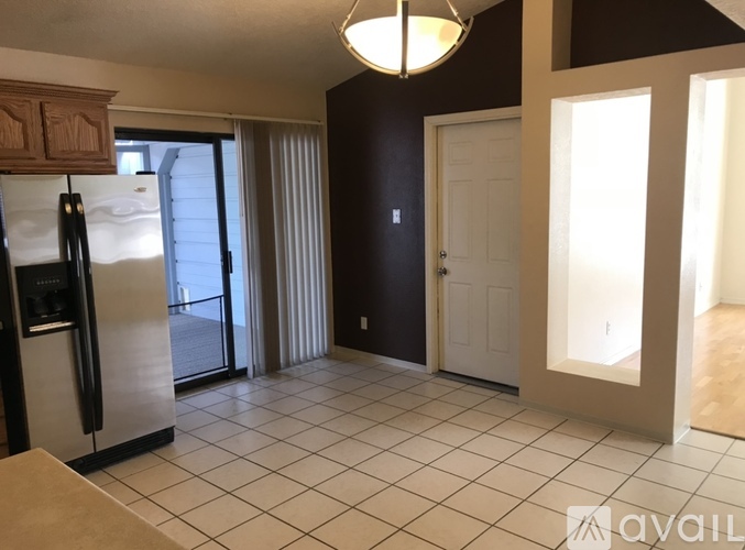 A kitchen with a refrigerator, a door, and a window.