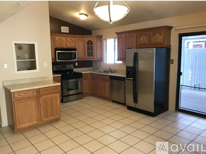 A kitchen with wooden cabinets and a black refrigerator.