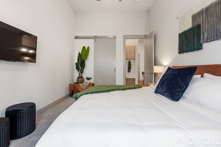 A bedroom with a large bed and a green plant in the corner.