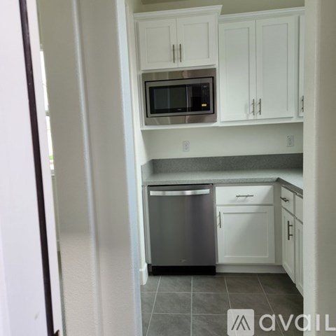 A kitchen with white cabinets and a stainless steel dishwasher.