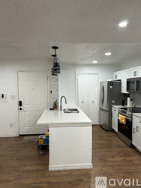 A kitchen with a white countertop and wooden floors.