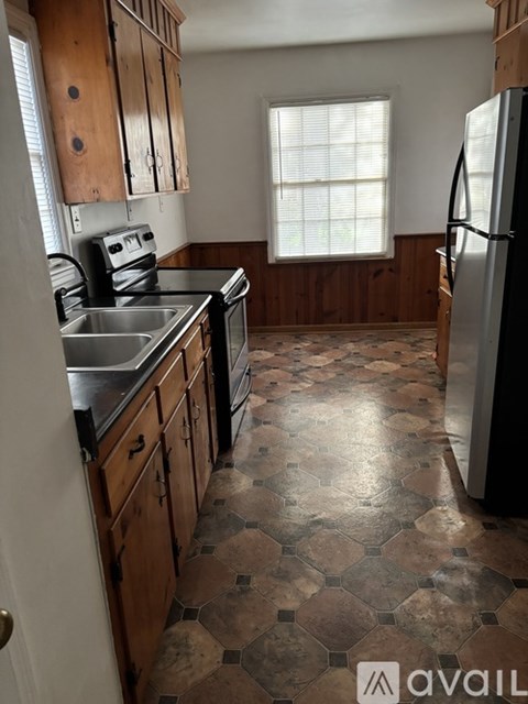 A kitchen with wooden cabinets and a tiled floor.