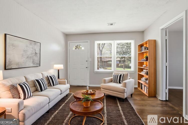 A living room with a white couch, a wooden coffee table, and a painting on the wall.
