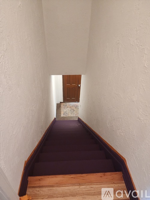 A long hallway with a wooden staircase.