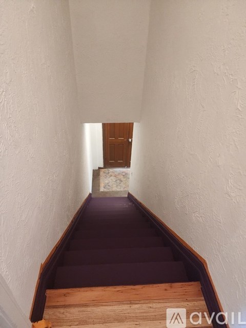 A long hallway with a wooden staircase.