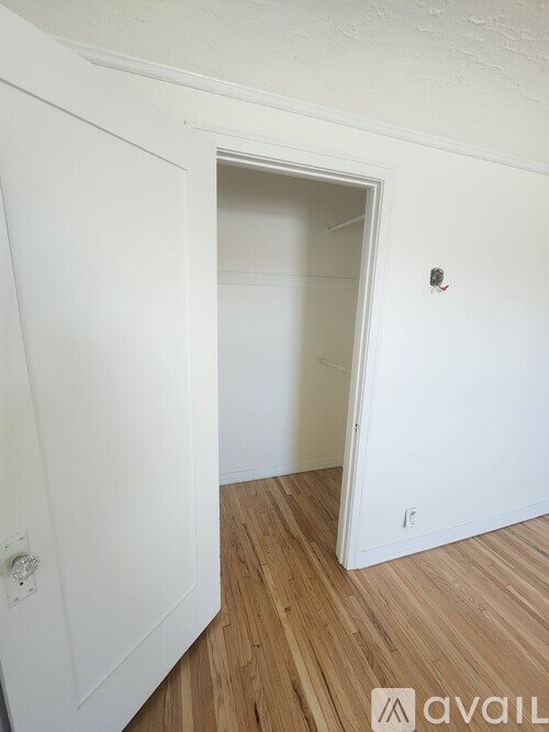 A white door is open to a room with wooden flooring.