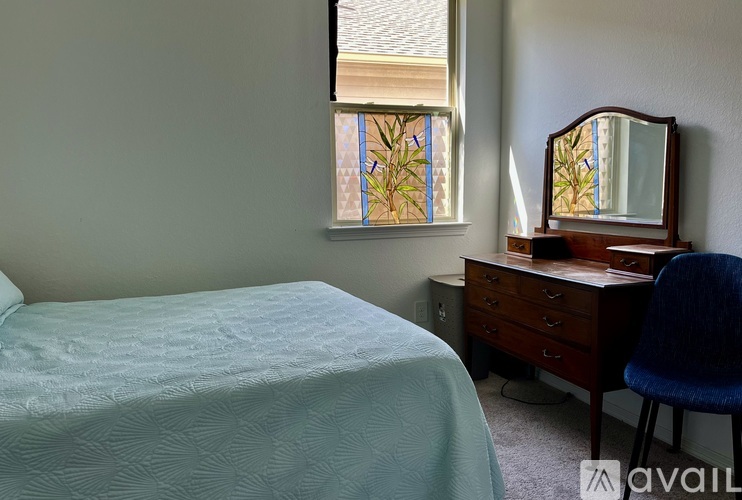 A bedroom with a bed, desk, chair, and window.