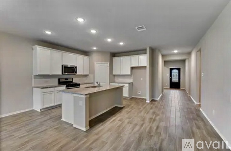 A spacious kitchen with white cabinets and a wooden floor.