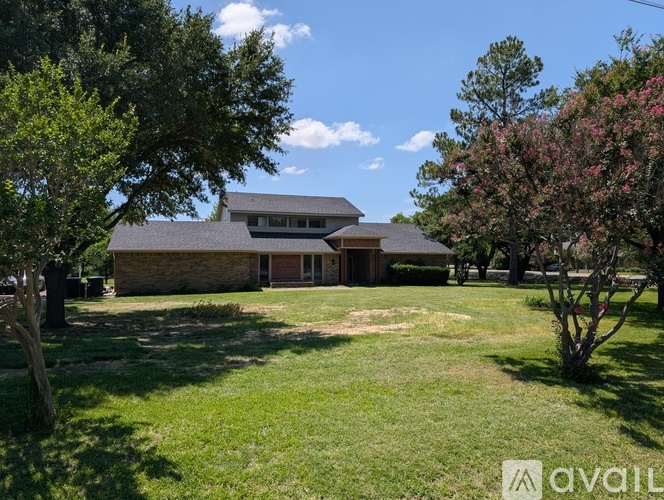 A house with a lawn and trees in front of it.