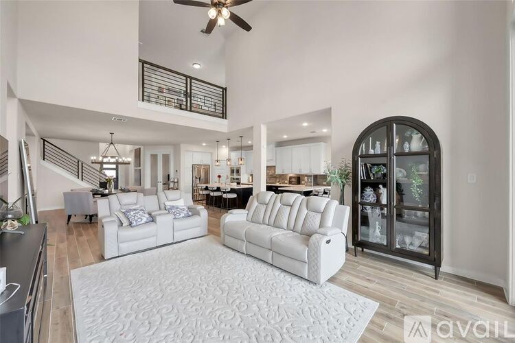 A spacious living room with white furniture and a staircase.