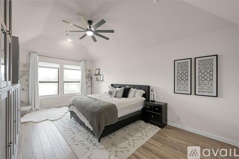 A bedroom with a large bed and a ceiling fan.