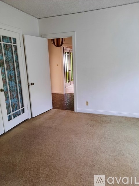 A room with a carpeted floor and a door leading to another room.