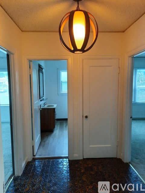 A hallway with a rug and a light hanging from the ceiling.