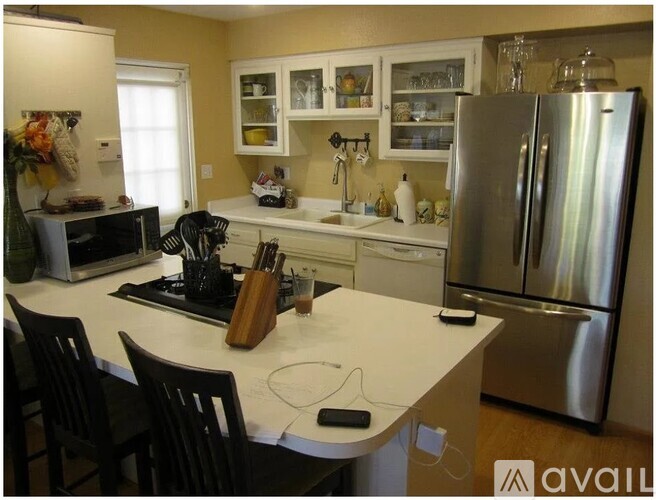 A kitchen with a white counter top and a stainless steel refrigerator.