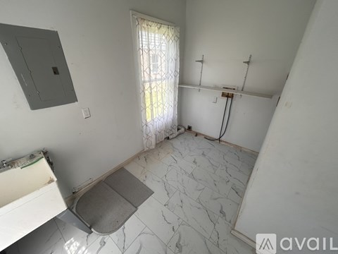 A bathroom with a white tiled floor and a window with a curtain.