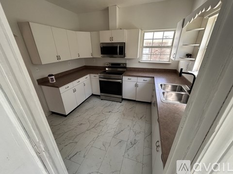 A kitchen with white cabinets and a brown countertop.