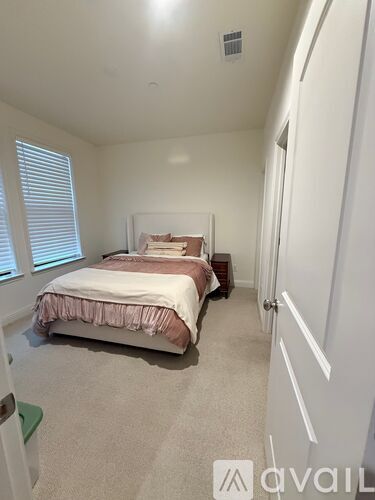 A bedroom with a bed and a window with blinds.