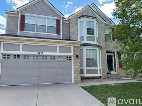 A two-story house with a garage and a driveway.