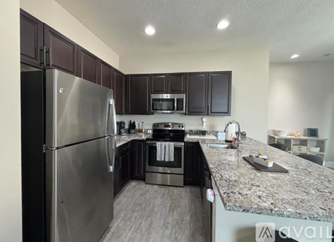 A kitchen with dark brown cabinets and a granite countertop.