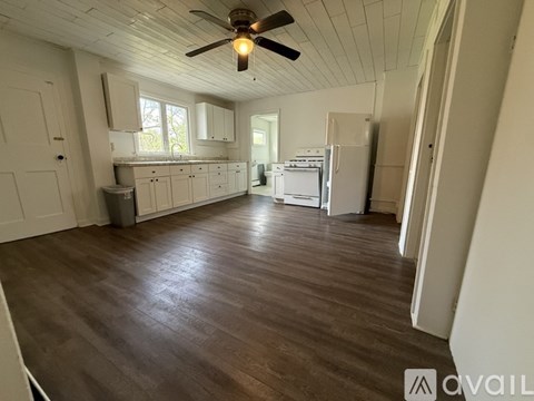 A spacious kitchen with white cabinets and a ceiling fan.