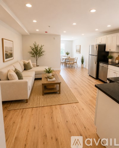 A modern living room with a couch, coffee table, and kitchen area.