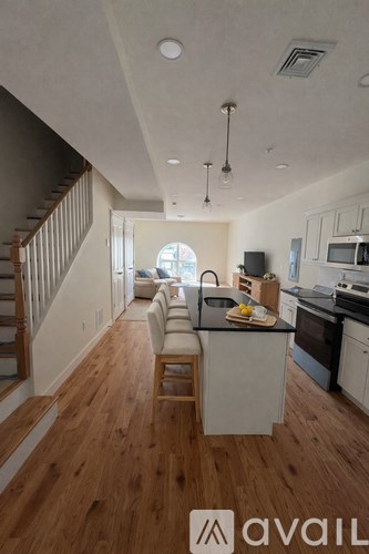 A modern kitchen with wooden floors and a staircase on the left.