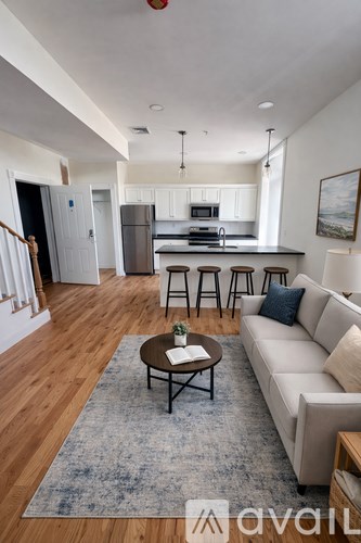 A living room with a couch, coffee table, and a kitchen in the background.